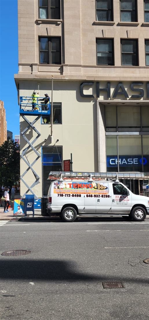 Tekno Construction branded van and scissor lift at a Chase bank facade repair project in New York — LL11 facade repairs contractor at work