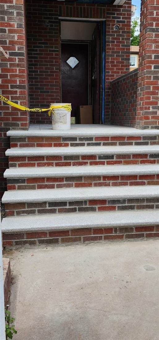 Newly rebuilt brick porch steps with fresh granite treads at a home entrance — masonry work by Tekno Construction