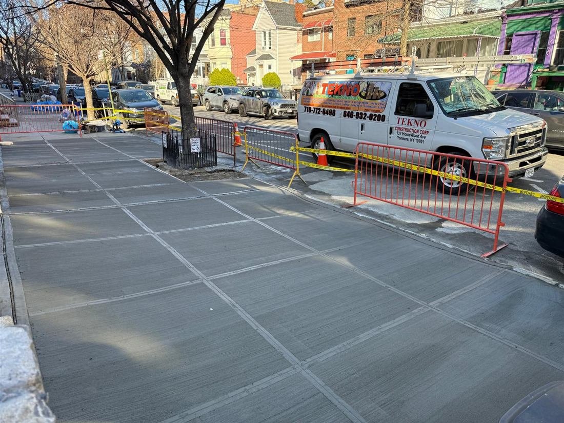 Freshly poured and finished concrete sidewalk by Tekno Construction crew in NYC