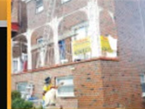 Workers restoring a brick apartment building exterior for Tekno Construction